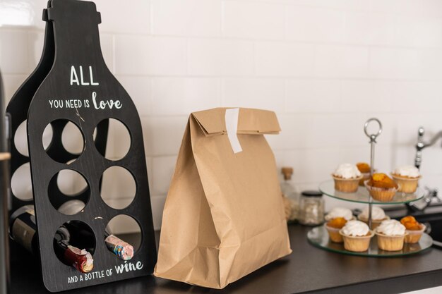사진 유기농 식품 라벨, 음식 배달 서비스, 복사 공간이 있는 흰색 주방 내부의 나무 테이블에 있는 공예 종이 가방의 배경 이미지.