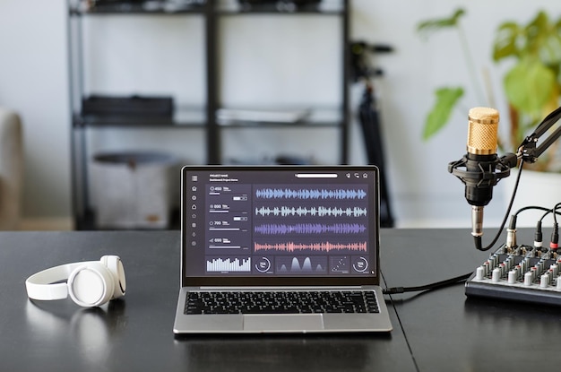 Фото Фоновое изображение студии звукозаписи с микрофоном и звуковыми дорожками на экране ноутбука