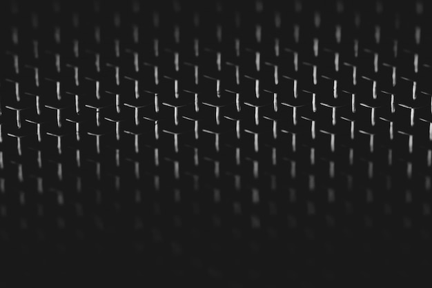 Background image of shiny mesh on dark backdrop. Metallic texture of grid close-up. Triangular shape of grid. Abstract image of surface of audio speaker in macro photography. Futuristic design.