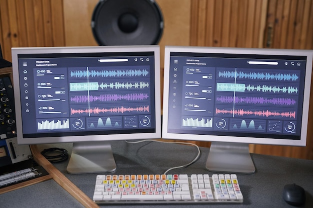 Photo background image of two computer screens with audio tracks in home recording studio music production