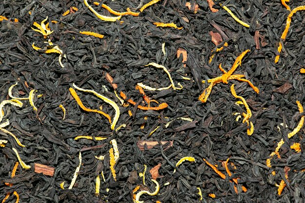 Фото Фон в виде свободного чая с апельсиновой кожурой, лимоном и кусочками корицы, текстура черного чая