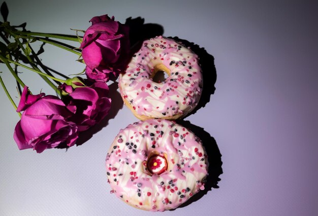 Background for International Women's Day with donuts in the shape of figure eight and pink roses