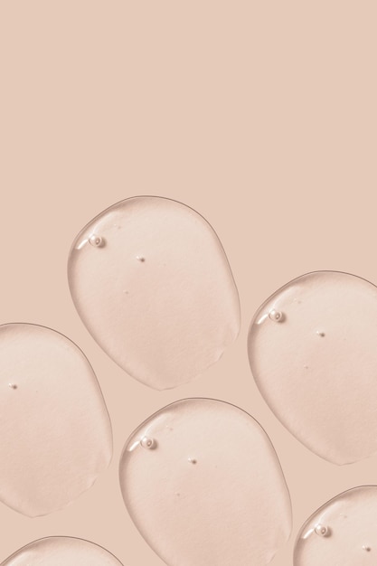 The background is cosmetic Many smears of transparent gel on a pink beige background