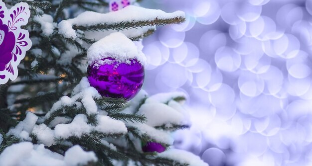 Foto lo sfondo è un albero di natale coperto di neve con giocattoli viola con un bel lato