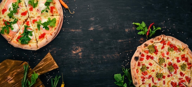 Foto sfondo di cibo italiano assortimento di pizza su uno sfondo di legno nero spazio libero per il testo vista dall'alto