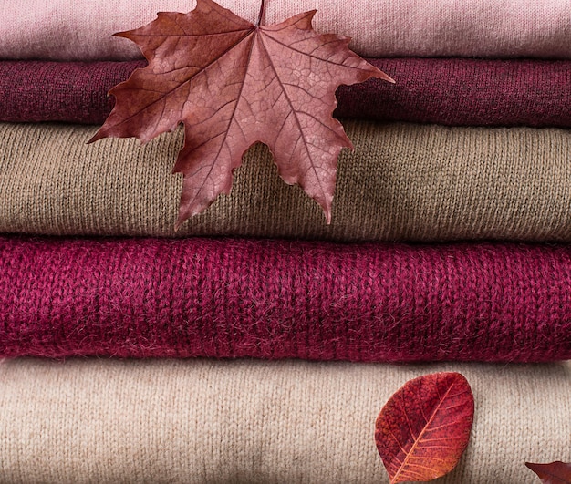 Sfondo di vestiti di lana lavorati a maglia con foglie autunnali trama lavorata a maglia