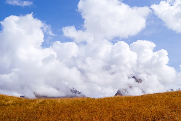 Background, landscape - mountain steppe and peaks hidden by clouds in the distance