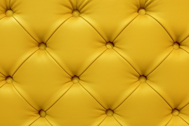 Background of leather yellow sofa, stitched buttons.