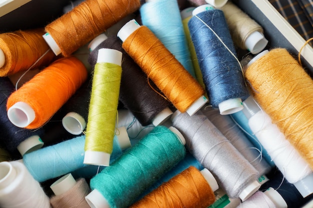 Background of many colorful spools of thread closeup Sewing hobby concept Pile of threads bobbins