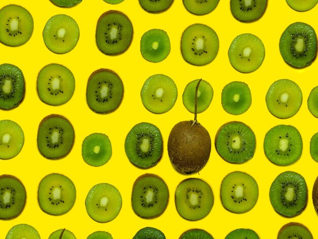 Photo background of many kiwi slices one whole in the peel sliced kiwi on a yellow background raw food concept sliced fruits pattern of green ripe fruit