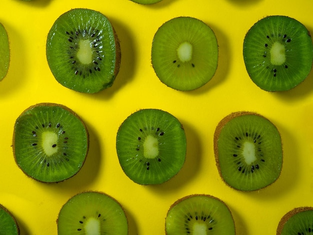 Background of many kiwi slices Sliced kiwi on a yellow background Raw food concept Sliced fruits Pattern of green ripe fruit
