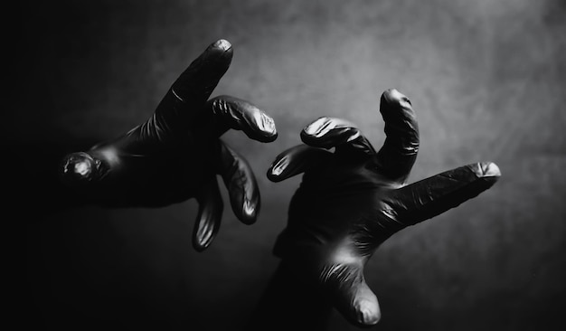 黒い手袋の手の背景。ホラーとハンドモンスター。黒い手のジェスチャー。