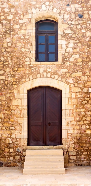 The background old beige stony wall with door and a window