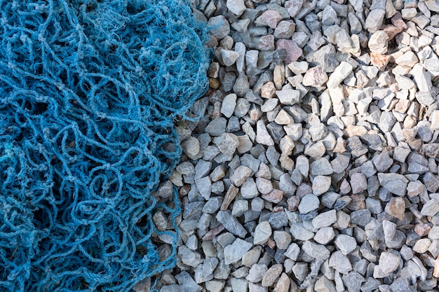 Background of pebbles with fishing net Pebble texture with a blue tint Decorative rocks