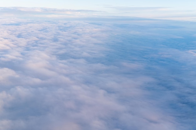 飛行機から見たふわふわの密な雲の上面とピンク紫の天国の空の背景スカイグラデーション