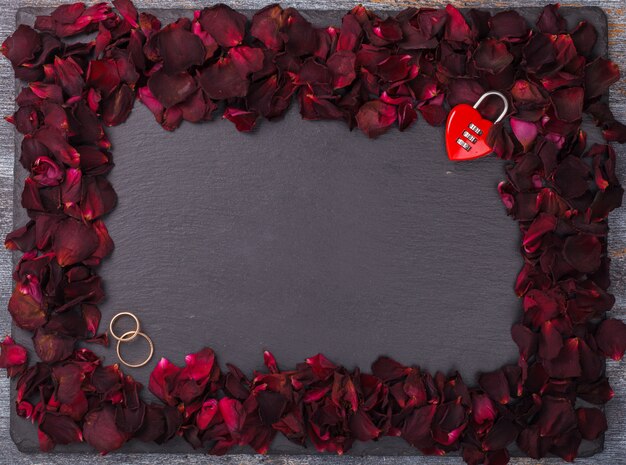 Photo background of red rose petals and wedding rings.