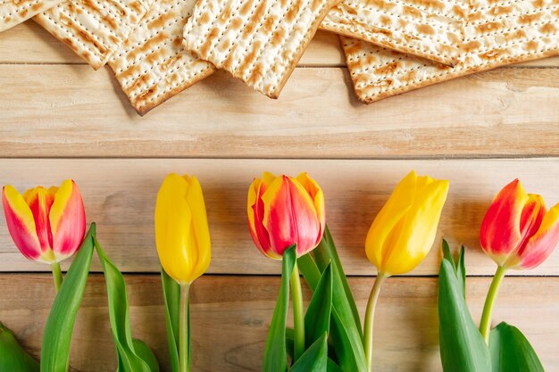 Background Religious Jewish holiday Pesach Tulips and matzo on a light wooden table Happy Passover