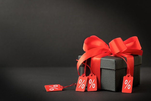 Background for sales with black gift box with red ribbon and lables