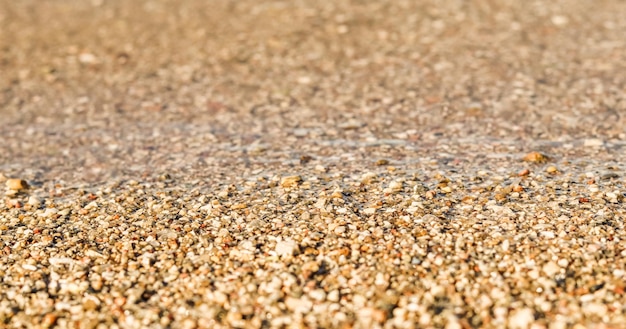 모래 작은 자갈과 바다 해변에 흐르는 파도의 배경 여름 휴가 개념