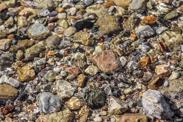 海のビーチの砂、石、流れる波の背景。夏休みと沿岸の自然の概念