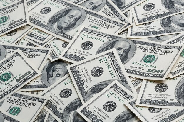 Photo a background of scattered hundred dollar bills. view from above.
