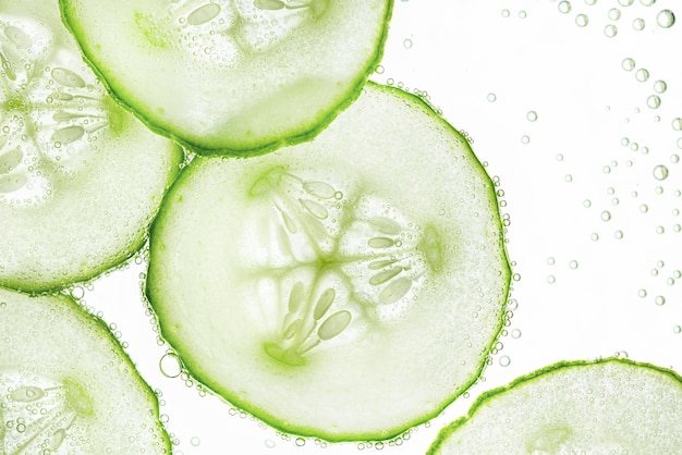 background of sliced cucumber slices with air bubbles on the water surface top view