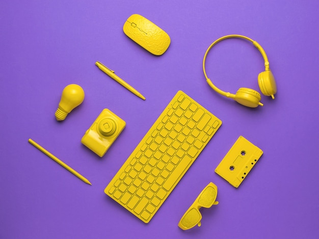 A background of stylish yellow computer accessories on a purple background. The concept of business and minimalism. Flat lay.