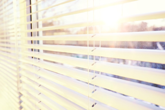 Background the sun shines in the spring through the metal\
blinds on the window the texture of the blinds