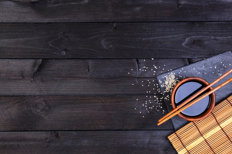 Photo background for sushi. bamboo mat and soy sauce on black wooden table. top view with copy space