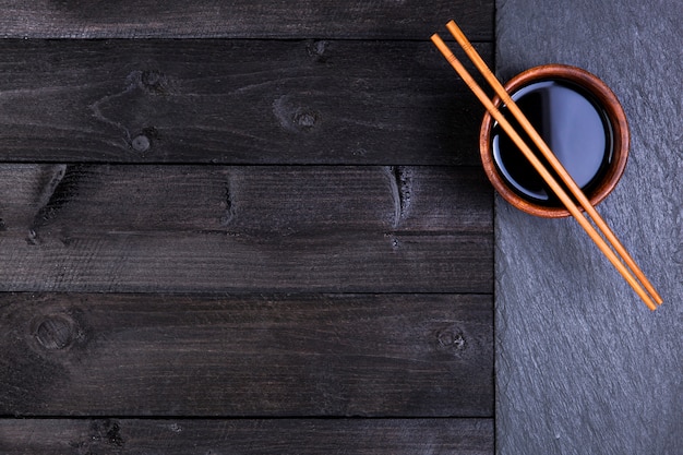 寿司の背景。醤油、黒い石の上に箸。コピースペースの平面図
