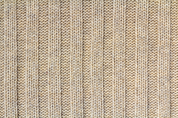 Background texture of beige pattern knitted fabric made of cotton or wool closeup