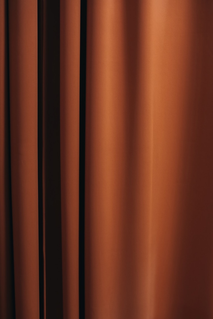 Photo background texture of orange material curtains details of a cozy home interior in autumn shades