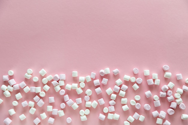 Photo background or texture of pink and white mini marshmallows on pink background with free space for text