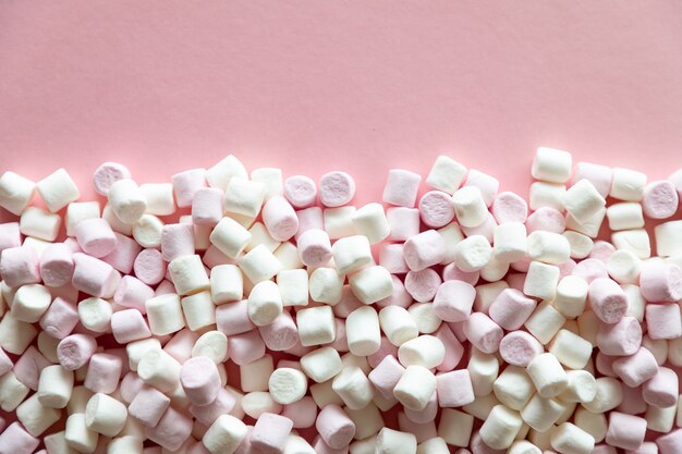 Background or texture of pink and white mini marshmallows on pink background with free space for text