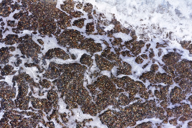 Фон, текстура морской воды с пеной и галькой.