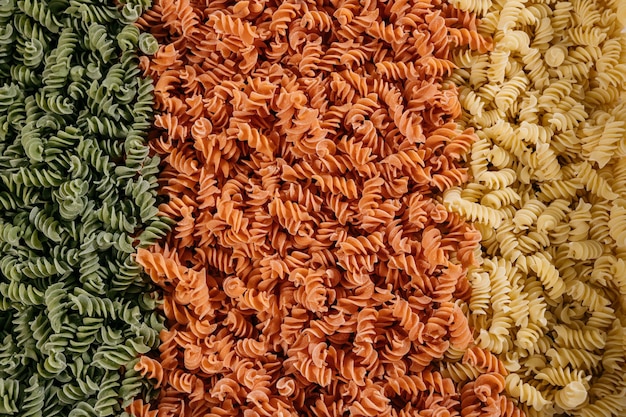 Background texture of tricolor fusilli pasta for traditional Italian and Mediterranean cuisine in a close up full frame view. High quality photo