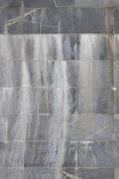 Background texture of a wall from an old gray granite tiles