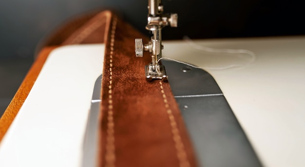 Background type of sewing machine, leather belt sewing process. Leather workshop.