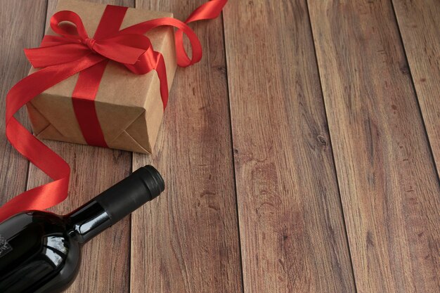 발렌타인 데이 배경 크래프트 종이에서 선물로 받은 와인 한 병, 나무 배경에 하트와 새틴 빨간 리본