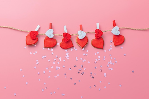 Background for Valentine's day from decorative hearts made of cookies hanging on slats on a pink background