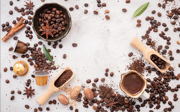 Foto sfondo di vari chicchi di caffè tostati scuri macinati e capsule con scoop su sfondo bianco in cemento con spazio per la copia