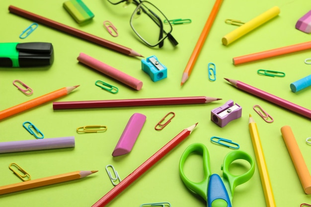 Background of various school supplies pencils, paper clips, crayons on a bright green background. Office tools. education. top view.