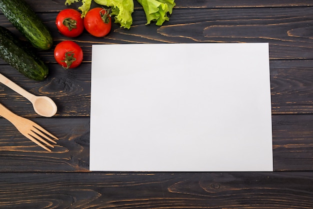 Background vegetables on a wooden background and a white sheet of paper. Copy space.