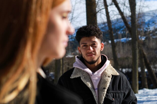 Background view of a young latin guy of a blonde caucasian girl's face in winter