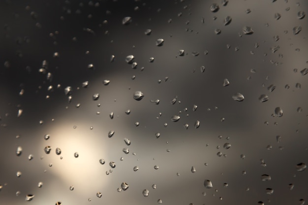 背景の水滴。窓ガラスの雨滴。雨滴の自然なパターン。ガラス上の雨滴の抽象的なショット。ガラスに降る雨の抽象的な降雨滴。碑文またはロゴの場所