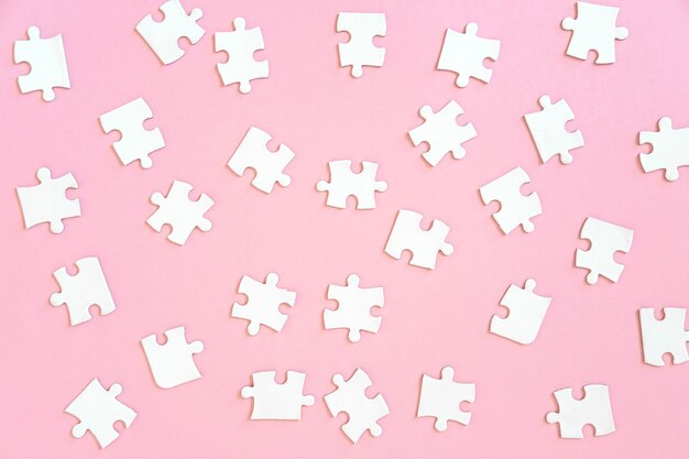 Background of of white jigsaw puzzle pieces on pink, top view