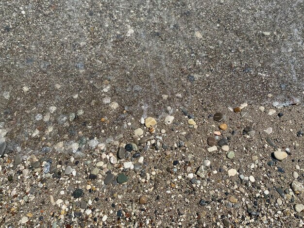 Фон белой морской гальки на пляже. Выборочный фокус размытых морских волн на заднем плане.