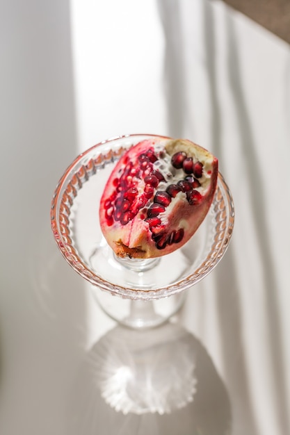 Background white with shadows from a crystal glass and pomegranate.