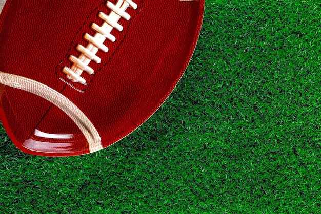 Background with american football plate on green grass.