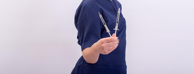 A background with a beautician in a blue robe holding syringes copy space